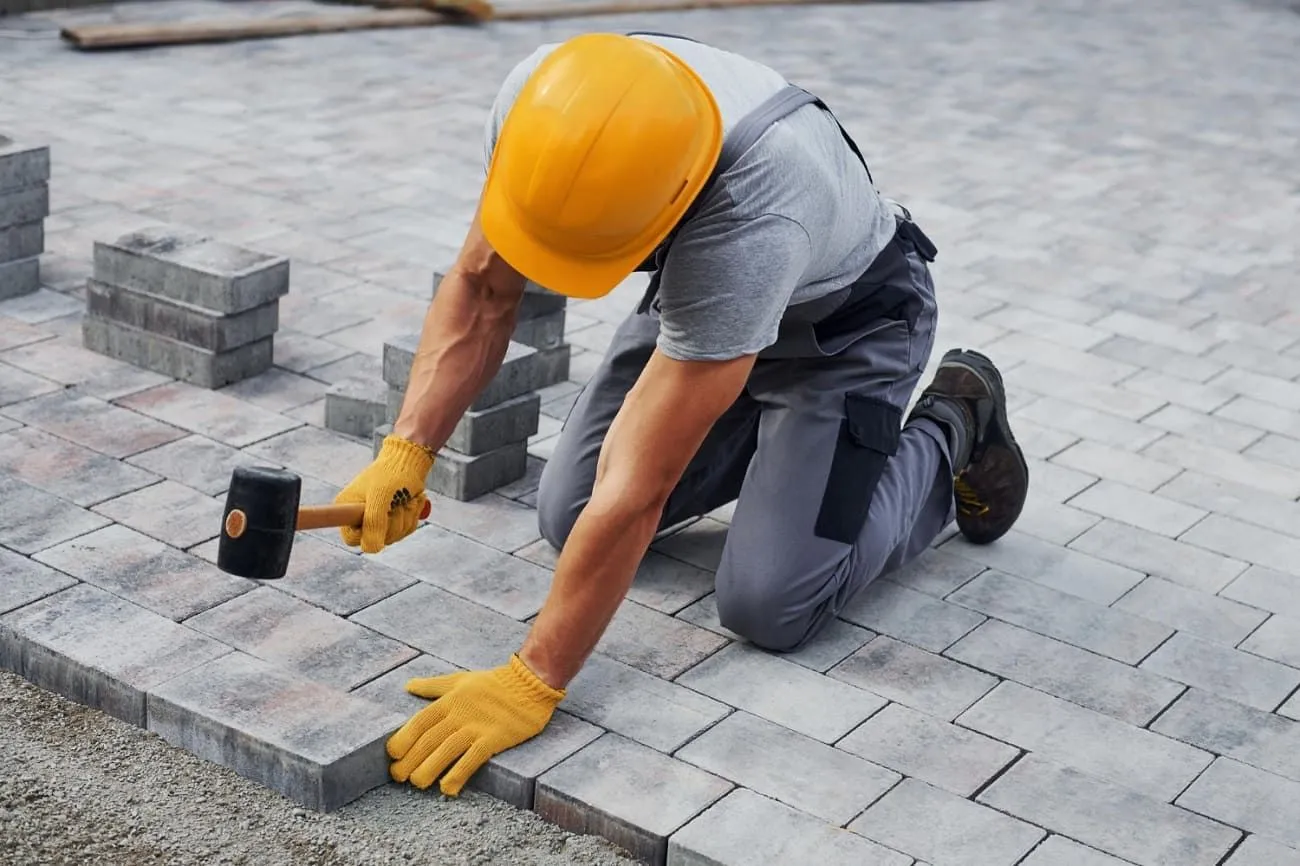 Paving contractor installing pavers on a driveway project